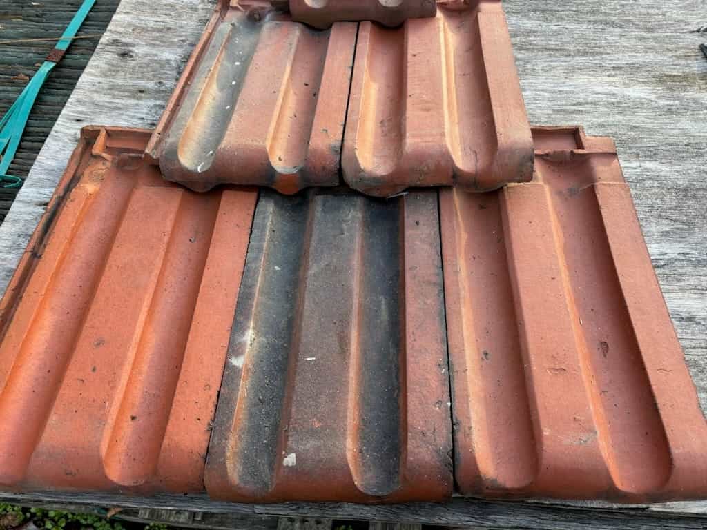 Salvaged Ludowici French 16¼ x 9 red smooth clay roof tile in reclaimed condition displayed close up.